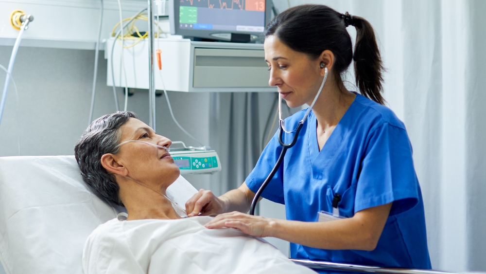Ein Patient im Krankenhausbett wird von einem Arzt mit einem Stethoskop untersucht