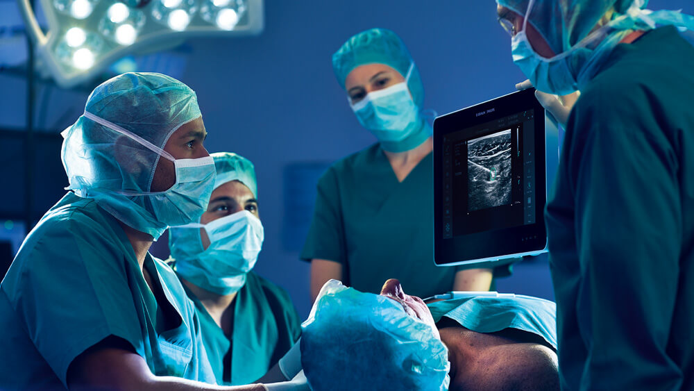 Medizinisches Personal beobachtet einen ultraschallgeführten infraklavikulären Plexusblock auf einem Monitor im Operationssaal