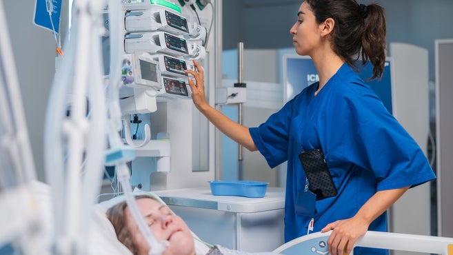 Krankenschwester bedient Geräte am Krankenbett mit Patientin