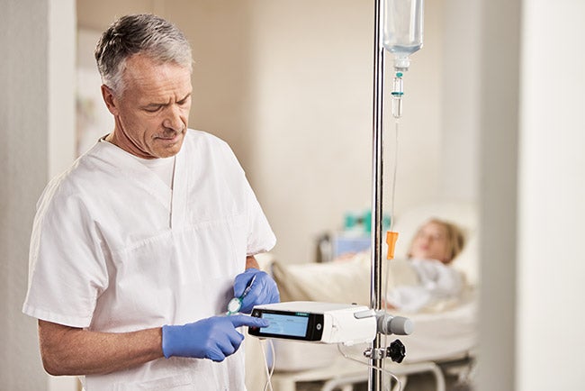 Pflegekraft tippt mit dem Finger auf das Display einer Infusionspumpe