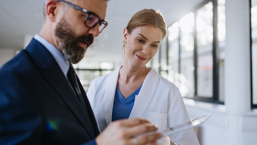Pharmaceutical sales representative talking with the female doctor in medical building. Hospital director consulting with healthcare staff.