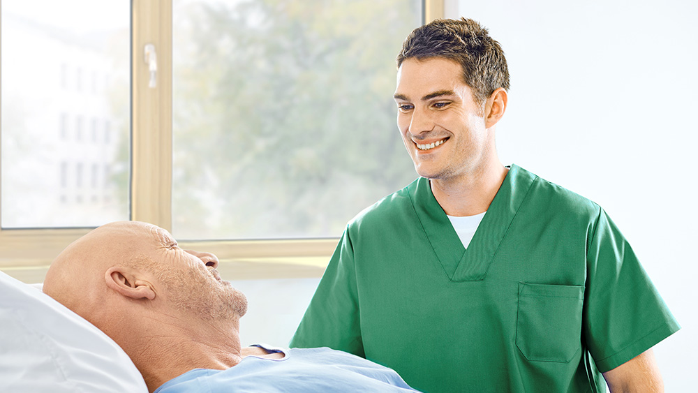 Pflegekraft und Patient in einem Krankenhauszimmer, beide lächelnd